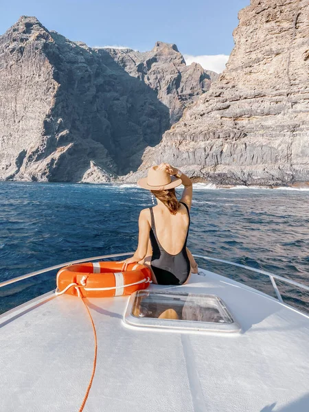 Mujer en la nariz del yate cerca de la costa rocosa — Foto de Stock