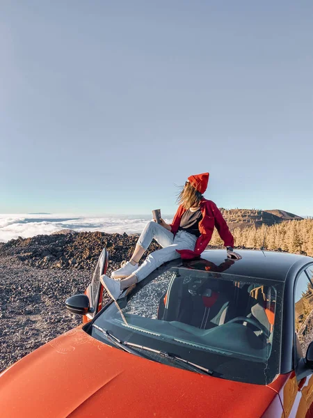 Frau genießt schönen Sonnenuntergang über den Wolken, unterwegs mit dem Auto — Stockfoto