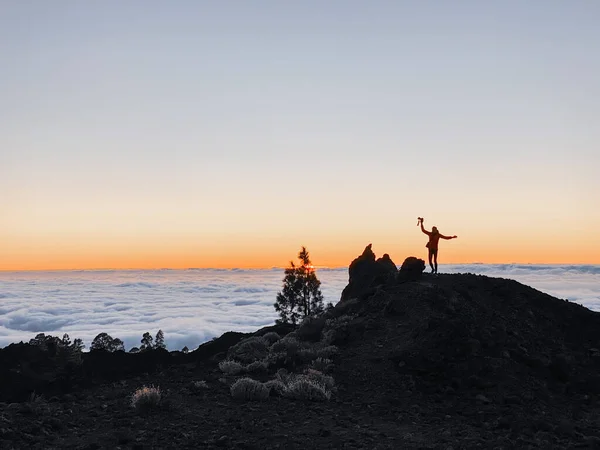 Männliche Silhouette auf der felsigen Landschaft über den Wolken — Stockfoto