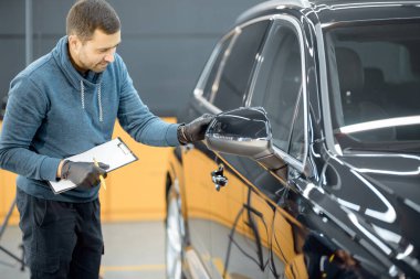 Worker examining vehicle body for scratches
