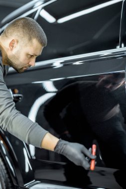 Worker examining vehicle body for scratches