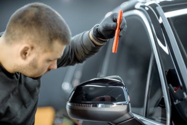Worker examining vehicle body for scratches