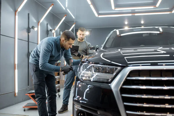 Workers examining vehicle body for scratches — Stock Fotó