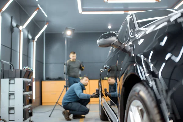 Працівники вивчають кузов автомобіля для подряпин — стокове фото