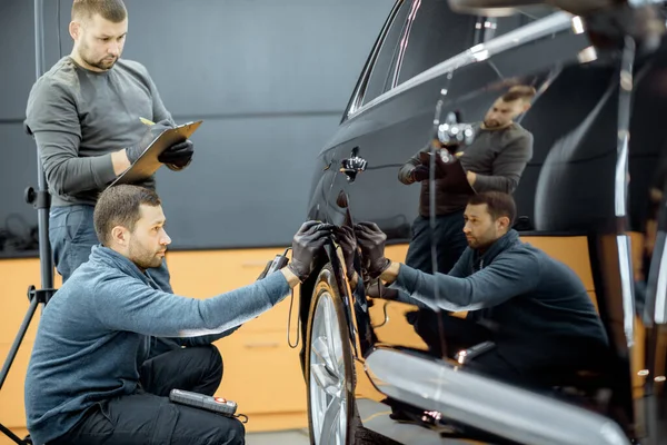 Workers examining vehicle body for scratches — Stock Fotó