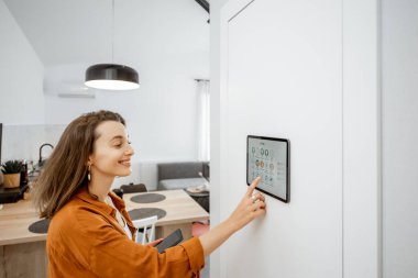 Woman controlling smart devices with a digital tablet at home