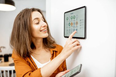Woman controlling smart devices with a digital tablet at home