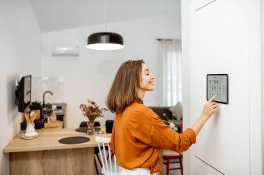 Woman controlling smart devices with a digital tablet at home