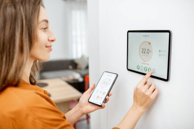 Woman controlling heating with a smart devices clipart