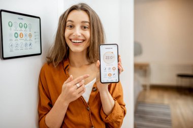Happy woman controlling smart home with a touch screen devices