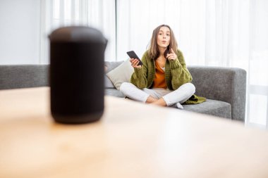 Woman controlling home devices with a voice commands