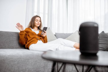 Woman controlling home devices with a voice commands