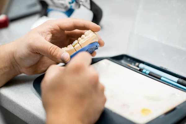Зубной техник раскрашивает зубной протез — стоковое фото