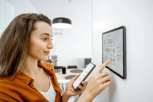 Donna che controlla i dispositivi intelligenti con un tablet digitale a casa — Foto Stock