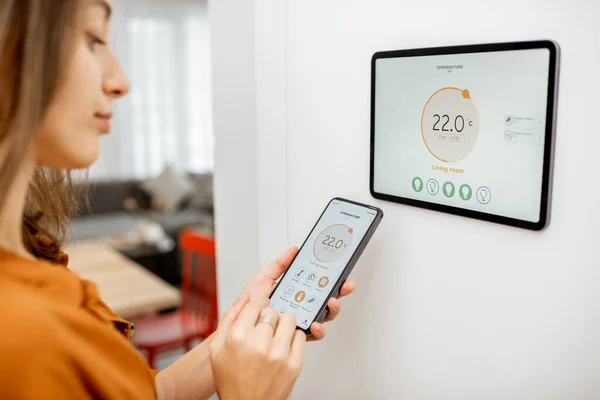 Woman controlling heating with a smart devices — ストック写真