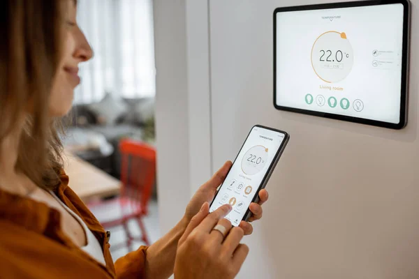Woman controlling heating with a smart devices — Stockfoto