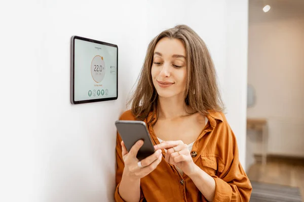 Woman controlling heating with a smart devices — Stockfoto