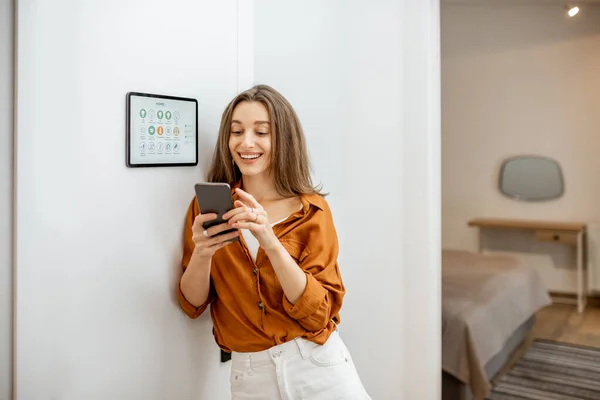 Portrait of a happy woman controlling smart home — Stockfoto