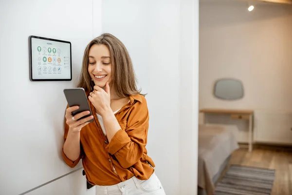 Portrait of a happy woman controlling smart home — Stockfoto