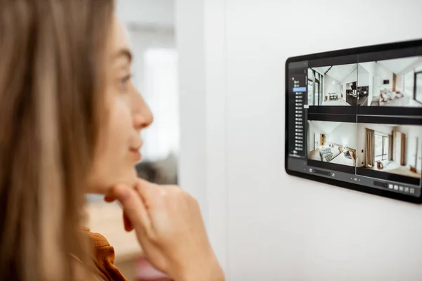 Woman controlling home with video cameras and digital tablet — Stok fotoğraf