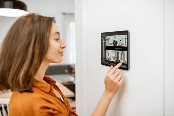 Woman controlling home with video cameras and digital tablet — Stok fotoğraf