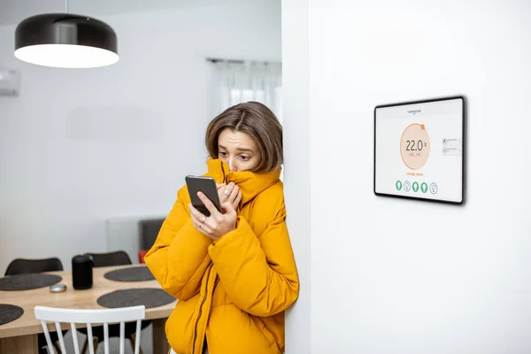 Mulher sentindo frio, controlando o aquecimento com dispositivos inteligentes em casa — Fotografia de Stock