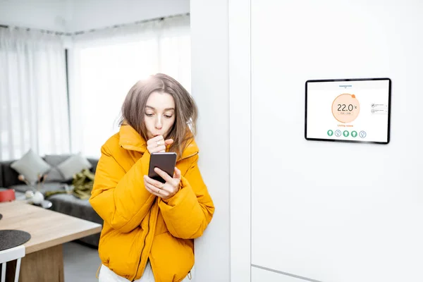 Женщина чувствует холод, контролируя отопление с помощью смарт-устройств дома — стоковое фото