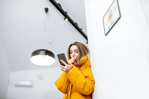 Woman feeling cold, controlling heating with a smart devices at home — Stockfoto