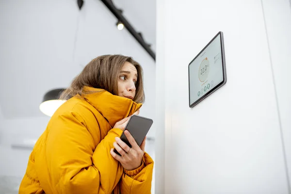 Donna che si sente fredda, controllando il riscaldamento con dispositivi intelligenti a casa — Foto Stock