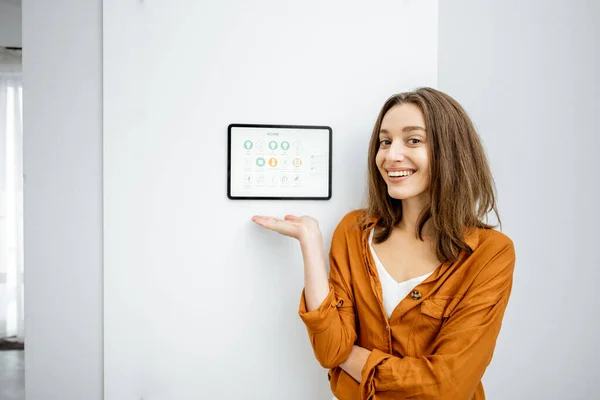 Portrait of a happy woman controlling home with a digital tablet — ストック写真