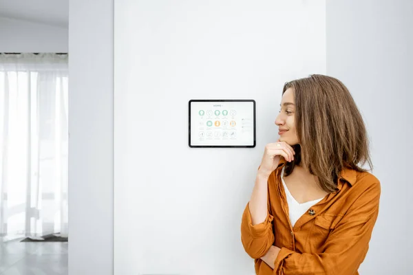 Portrait of a happy woman controlling home with a digital tablet — ストック写真