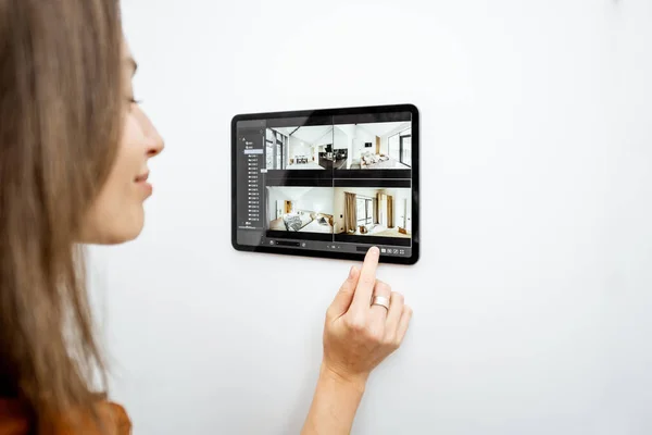 Woman controlling home with video cameras and digital tablet — Stock fotografie