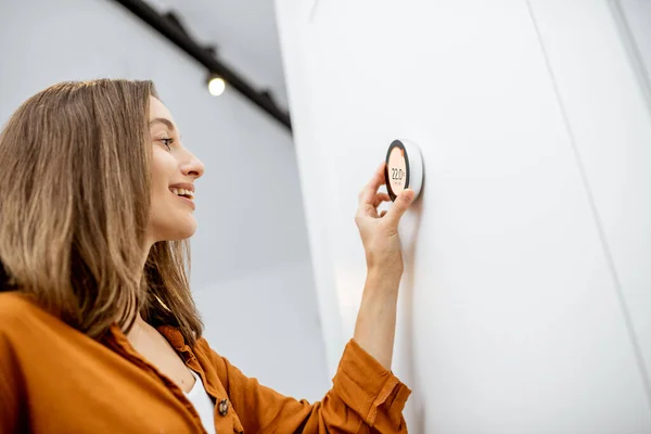 Woman regulating heating temperature at home — Stockfoto