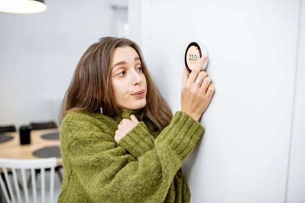Woman feeling cold controlling heating with a smart device at home — Stock Photo, Image