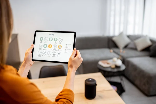 Woman controlling smart devices with a digital tablet at home