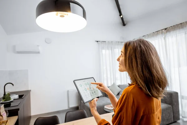 Woman controlling light with a digital tablet at home — Stockfoto