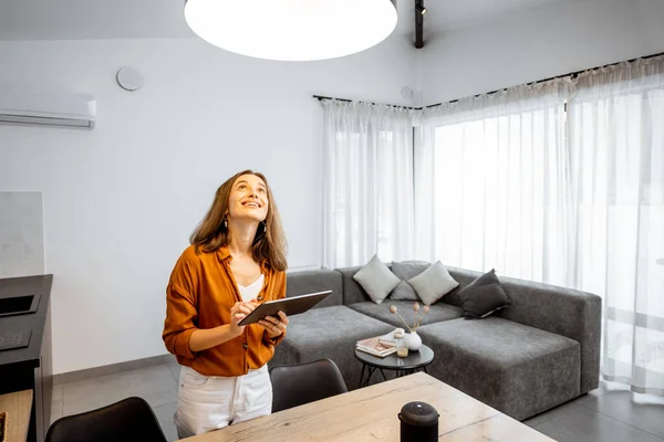 Mujer controlando la luz con una tableta digital en casa —  Fotos de Stock