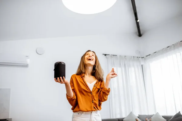 Woman controlling light with a smart speaker at home