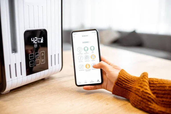 Controlling smart air humidifier with phone remotely at home — Stockfoto