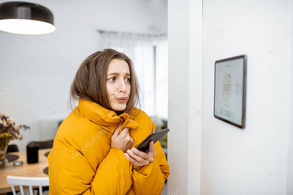 Cold woman controlling heating with a smart devices