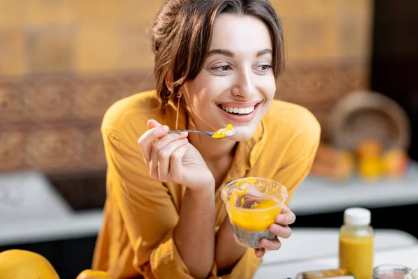 Woman eating chia pudding in the kitchen — Stock Photo, Image