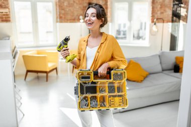 Portrait of a young handy woman with instruments at home
