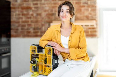 Portrait of a young handy woman with instruments at home