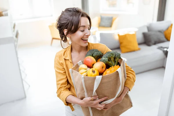 Mujer con bolsa llena de comida fresca en el interior —  Fotos de Stock