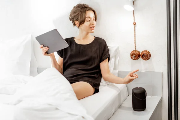 Femme relaxante avec un haut-parleur intelligent et une tablette dans la chambre — Photo