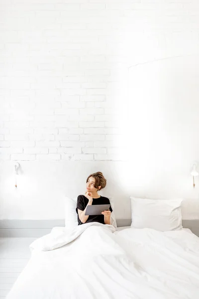 Woman relaxing with a digital tablet in the bedroom — 图库照片