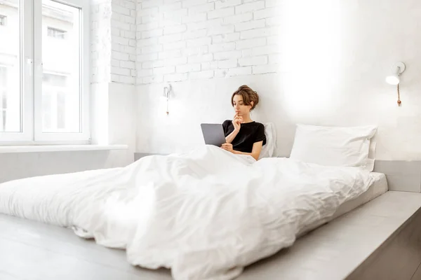 Mujer relajante con una tableta digital en el dormitorio — Foto de Stock