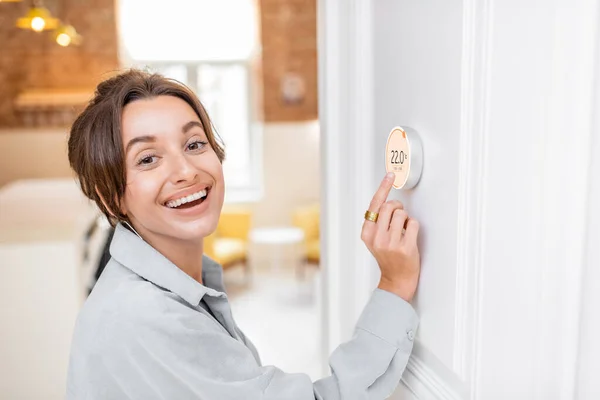 Mujer que regula la temperatura de calefacción con un termostato inteligente — Foto de Stock