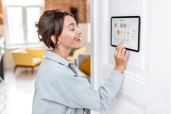 Frau steuert Haus mit digitalem Touchscreen — Stockfoto