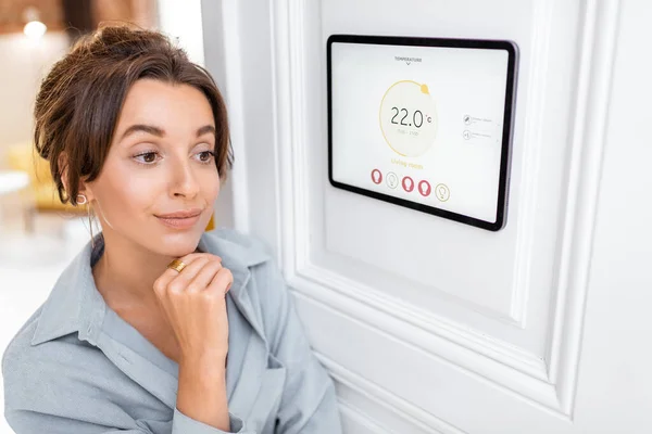 Frau steuert Raumtemperatur mit digitalem Touchscreen-Panel — Stockfoto